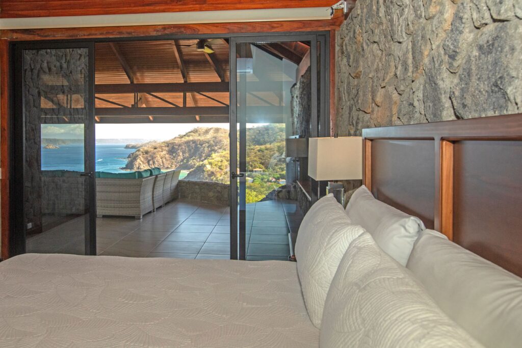 White bed in the master bedroom facing sliding doors and an ocean-view veranda