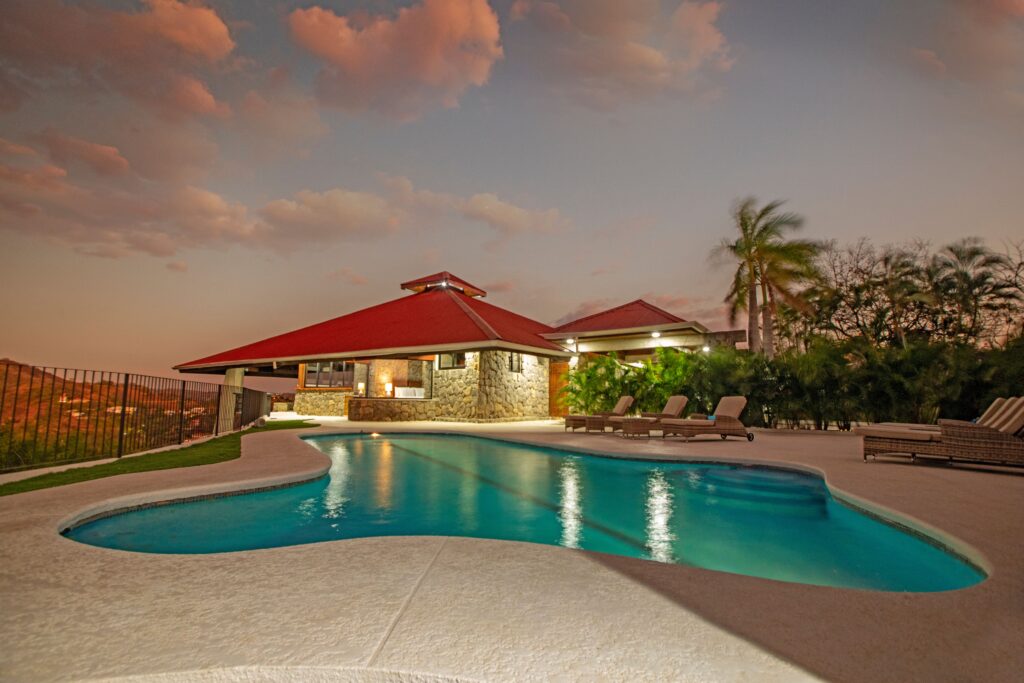 Curved swimming pool reflecting the lights of Villa Puerto Escondido at dusk