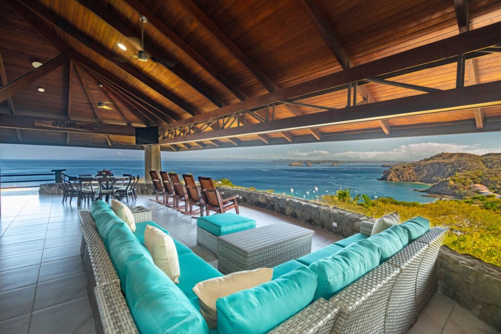 Covered veranda with turquoise seating, a dining area and panoramic views of Ocotal Bay