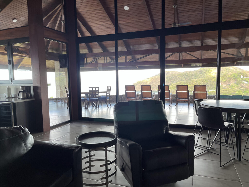 Living room with black leather seating and glass doors opening onto the ocean-view veranda