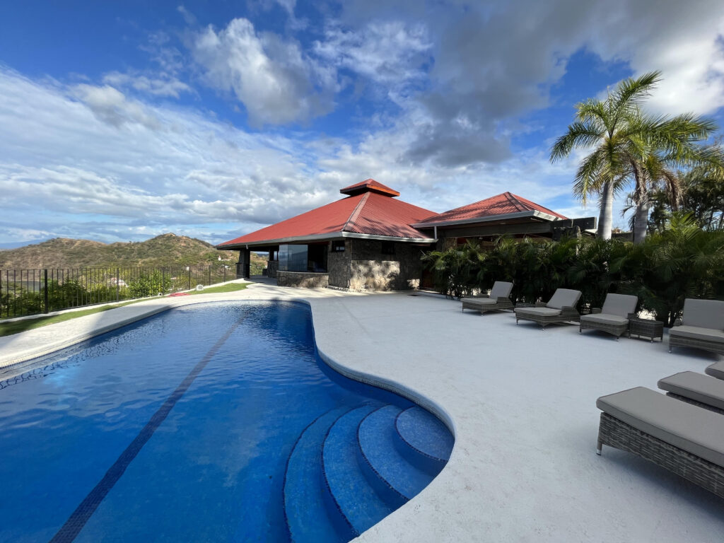 Swimming pool with curved entry steps, sun loungers and surrounding hills at Villa Puerto Escondido