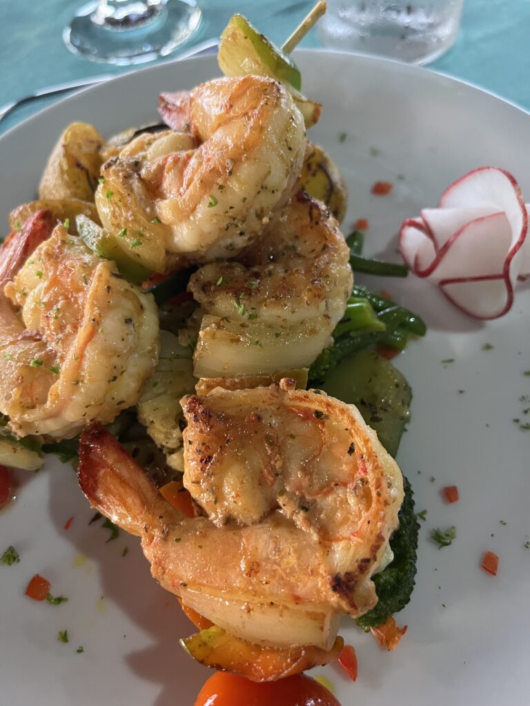 Grilled shrimp skewers served over roasted vegetables at Villa Puerto Escondido