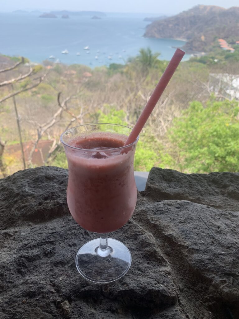Strawberry smoothie on a stone ledge overlooking boats in Ocotal Bay